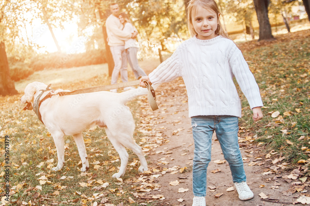 Little beautiful girl and parents walking with dog labrador in the park. Little beautiful girl and parents walking with dog labrador in the park.