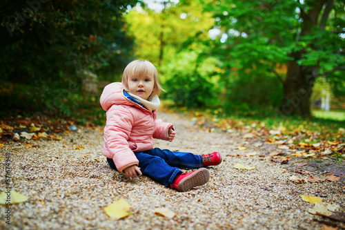 Adorable cheerful toddler girl in autumn park in Paris