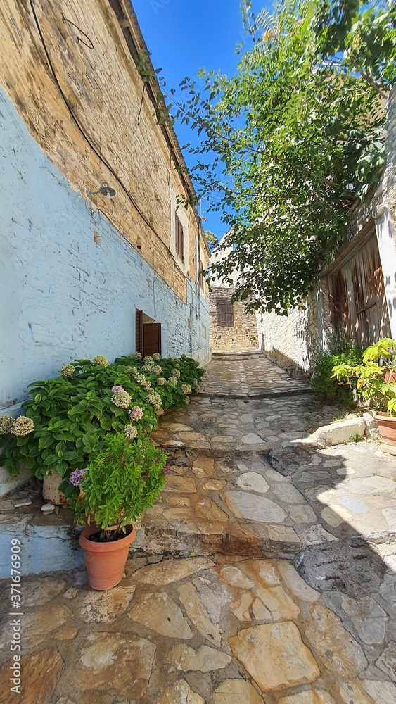 old stone house. Narrow street. Flowers in a pot