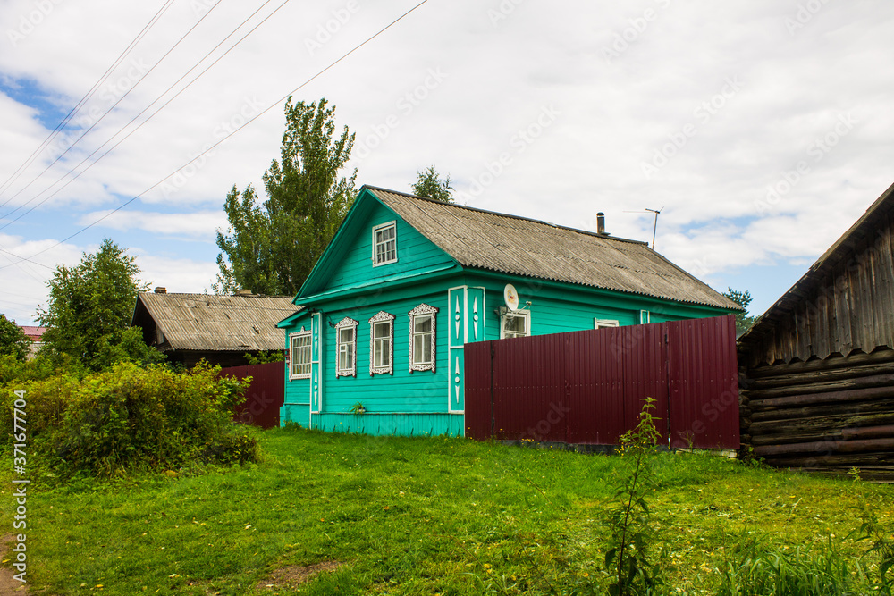 a street with old wooden Russian huts and green trees on a summer day and space for copying in Kalyazin Russia