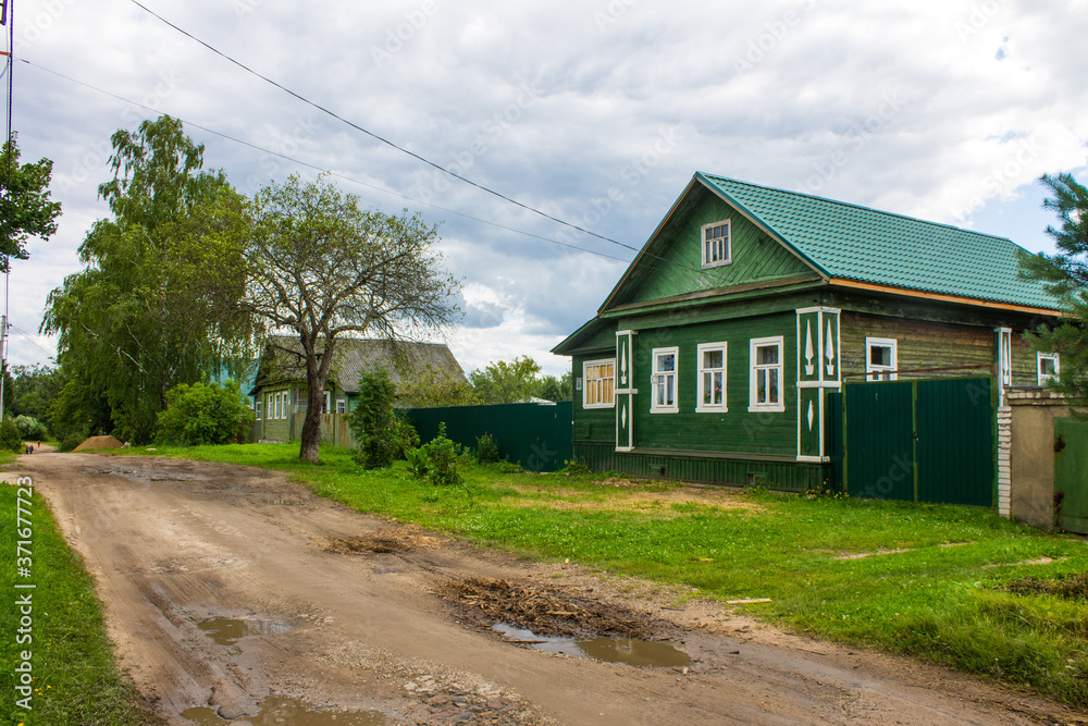 a street with old wooden Russian huts and green trees on a summer day and space for copying in Kalyazin Russia