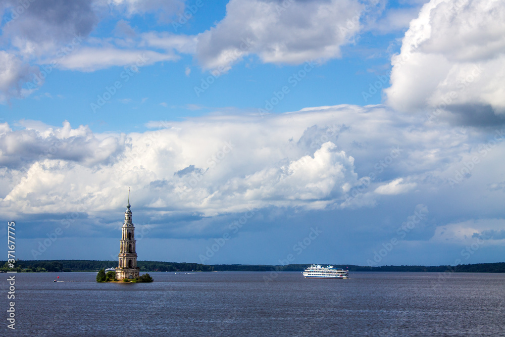 Obraz premium A submerged bell tower and a white cruise ship on the Volga river in Kalyazin Russia on a cloudy summer day and a copy space