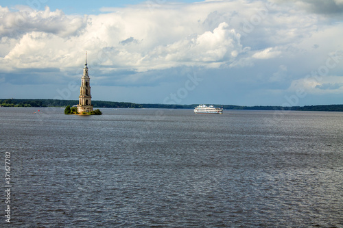 A submerged bell tower and a white cruise ship on the Volga river in Kalyazin Russia on a cloudy summer day and a copy space