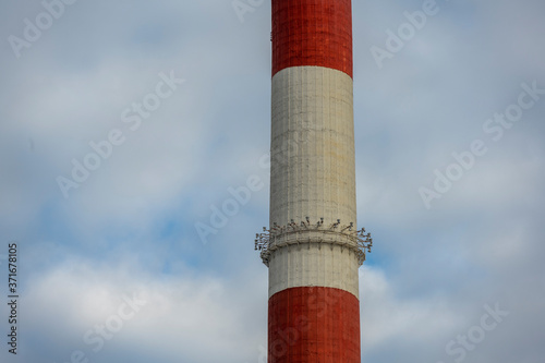 striped pipes of a large factory and a burning lantern
