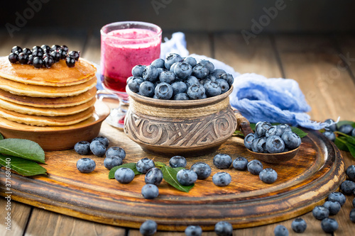 Blueberries in a plate and pancakes, on an old background.