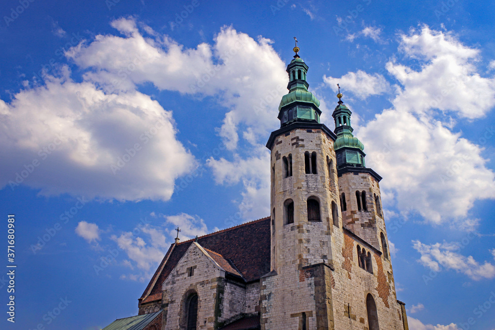 Towers Of An Ancient Catholic Church On A Background Of Blue Sky With White Clouds