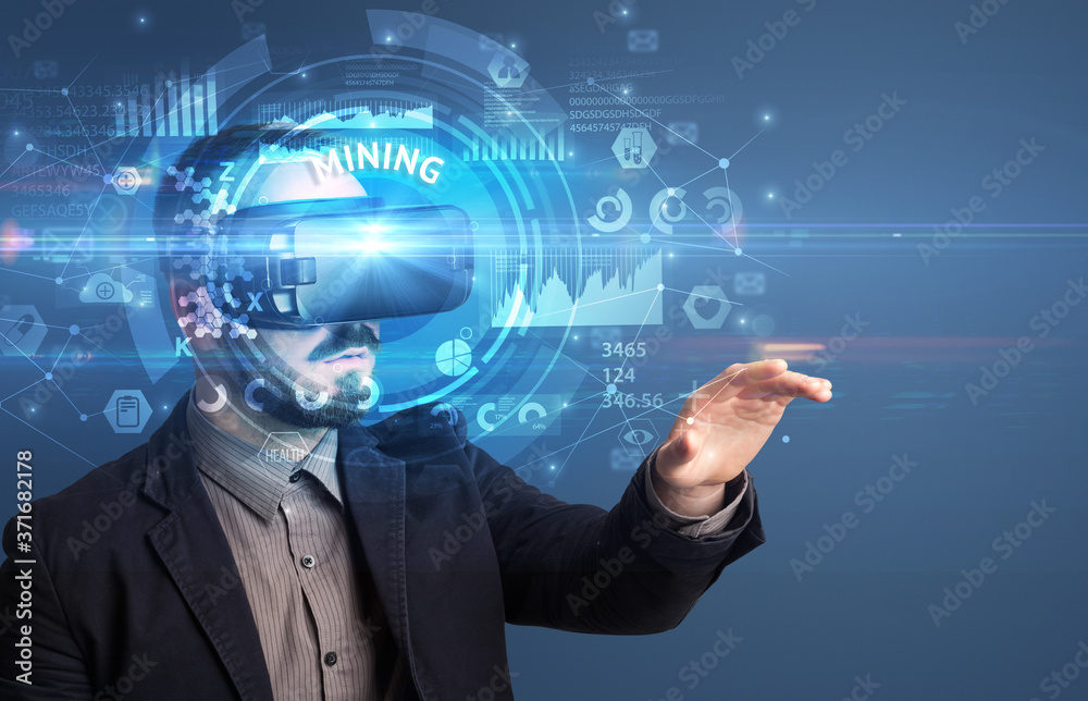 Businessman looking through Virtual Reality glasses with MINING inscription, innovative technology concept Businessman looking through Virtual Reality glasses with MINING inscription, innovative technology concept