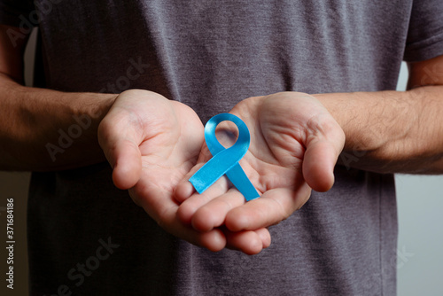 Man holding light blue ribbon. Awareness ribbon.