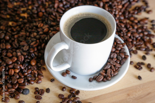  A cup of black coffee with coffee grains  natural light on wooden table