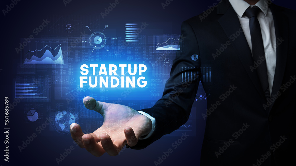 Hand of Businessman holding STARTUP FUNDING inscription, business success concept Hand of Businessman holding STARTUP FUNDING inscription, business success concept