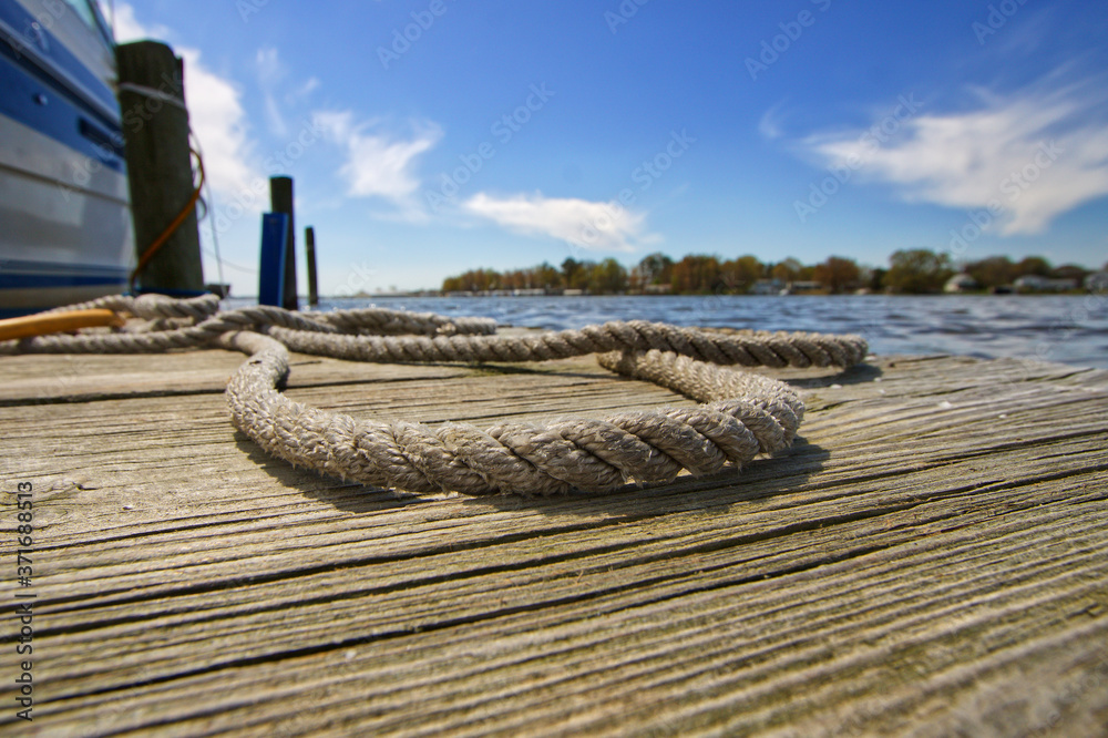 Obraz premium Dock Line Laying on the Boat Dock Next to a Boat on a Sunny Day