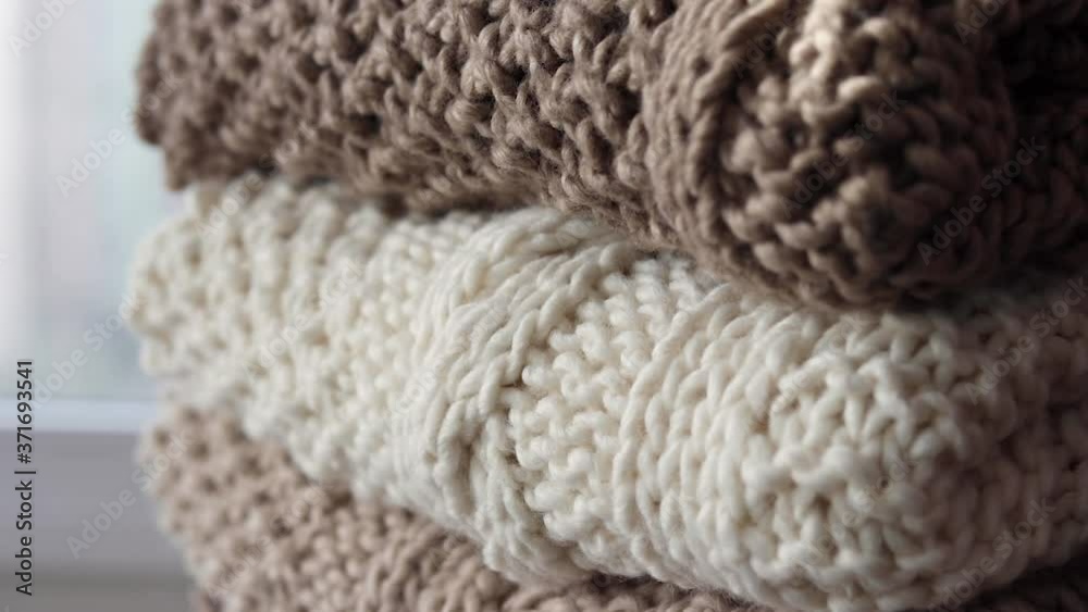 Detail of a pile of earth-colored handwoven blankets that are placed on a wicker chair. Detail of a pile of earth-colored handwoven blankets that are placed on a wicker chair.