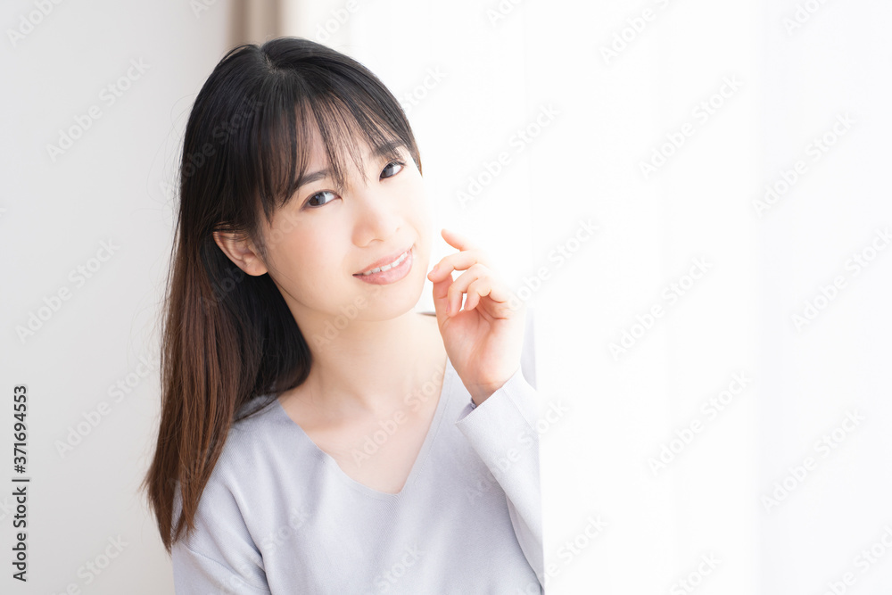 部屋の窓際に立つ若い女性 部屋の窓際に立つ若い女性