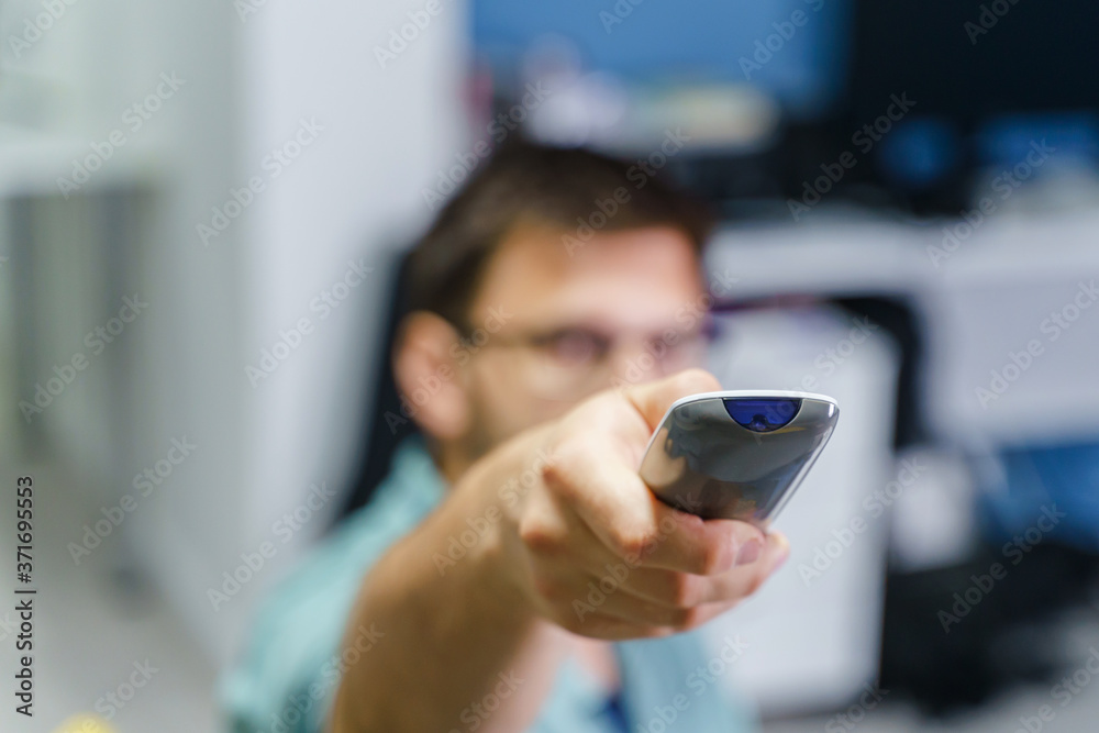 Close up on remote control of tv set or air condition device in hands of unknown caucasian man Close up on remote control of tv set or air condition device in hands of unknown caucasian man