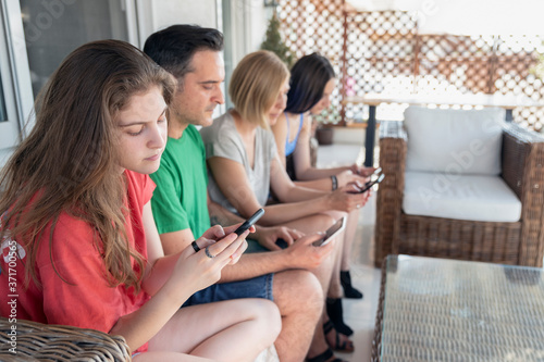 Family Sitting on a Sofa at the Balcony on addicted moment using mobile smart phones