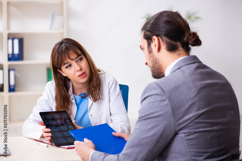 Fototapeta premium Young female doctor and sick businessman in the office