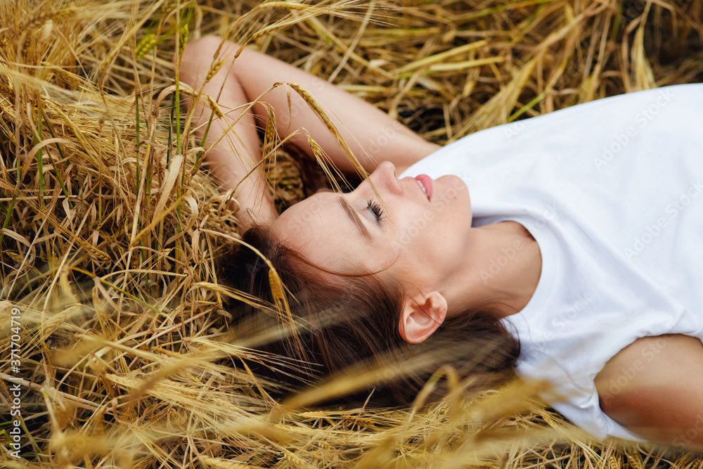 Photo of a girl in a field. Beautiful woman in a wheat field. The girl is lying in the wheat. Photo of a girl in a field. Beautiful woman in a wheat field. The girl is lying in the wheat.