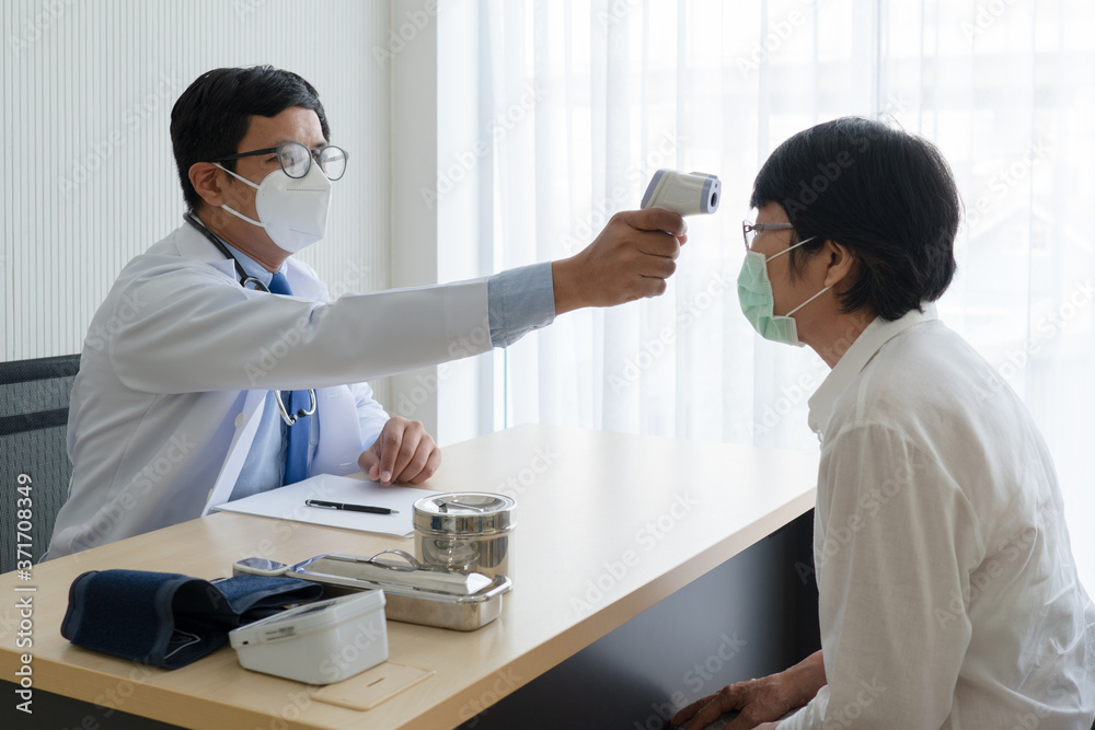 doctor using infrared digital thermometer to measure temperature of woman patient that was sick and came visit at the clinic in hospital. healthcare and medical concept