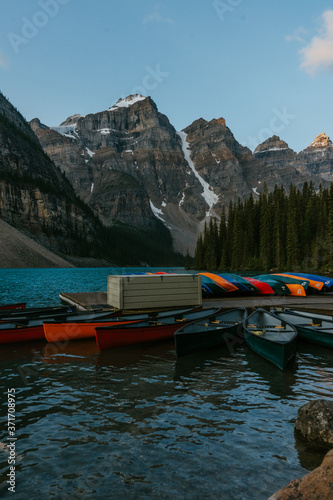 Colorful kayak boats on the beautiful iconic Moraine Lake in Canadian Rockies, Alberta, Canada. Sunrise mountain landscape on background.