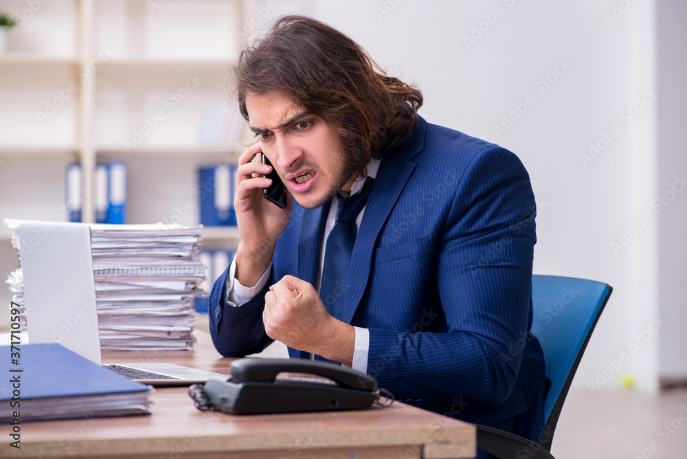Young male employee unhappy with excessive work Young male employee unhappy with excessive work