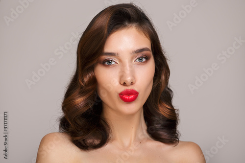 Portrait of beautiful brunette woman with retro hair style and makeup. Red lipstick and short hair