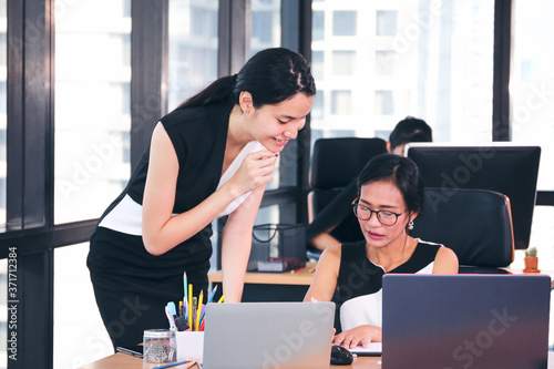 Business Lady officers discussing and working or using computer on desk in office with colleagues talking together with team
