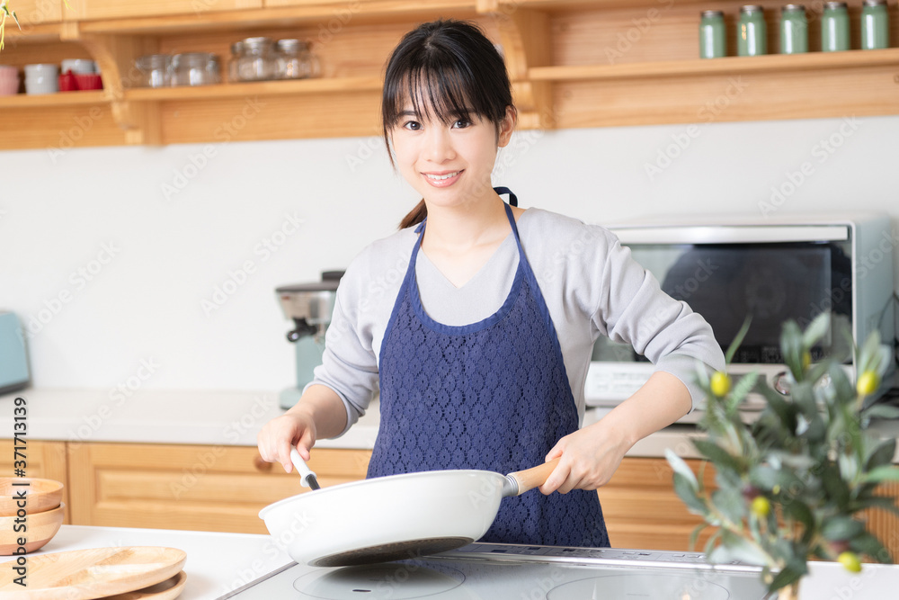 キッチンに立つエプロンを着た若い女性 キッチンに立つエプロンを着た若い女性