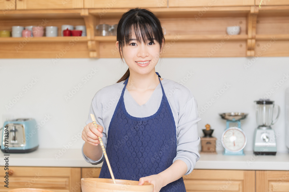 キッチンに立つエプロンを着た若い女性 キッチンに立つエプロンを着た若い女性
