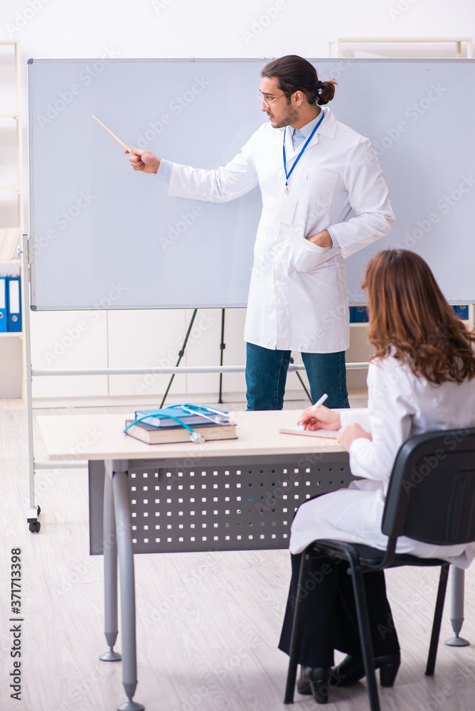 Young male teacher doctor and female student in the classroom Young male teacher doctor and female student in the classroom