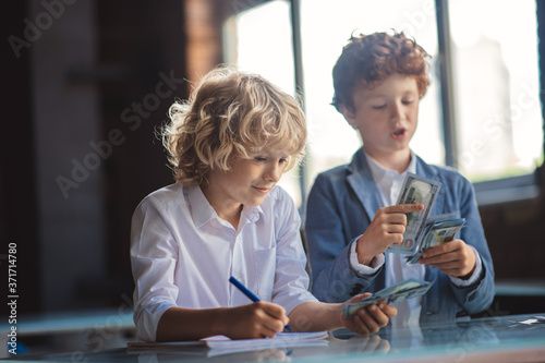 Two boys counting money and making notes