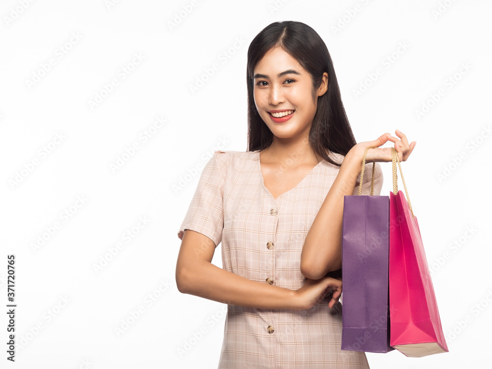 Portrait of smiling beautiful asian woman wearing dress and holding shopping bags isolated on white background. Portrait of smiling beautiful asian woman wearing dress and holding shopping bags isolated on white background.