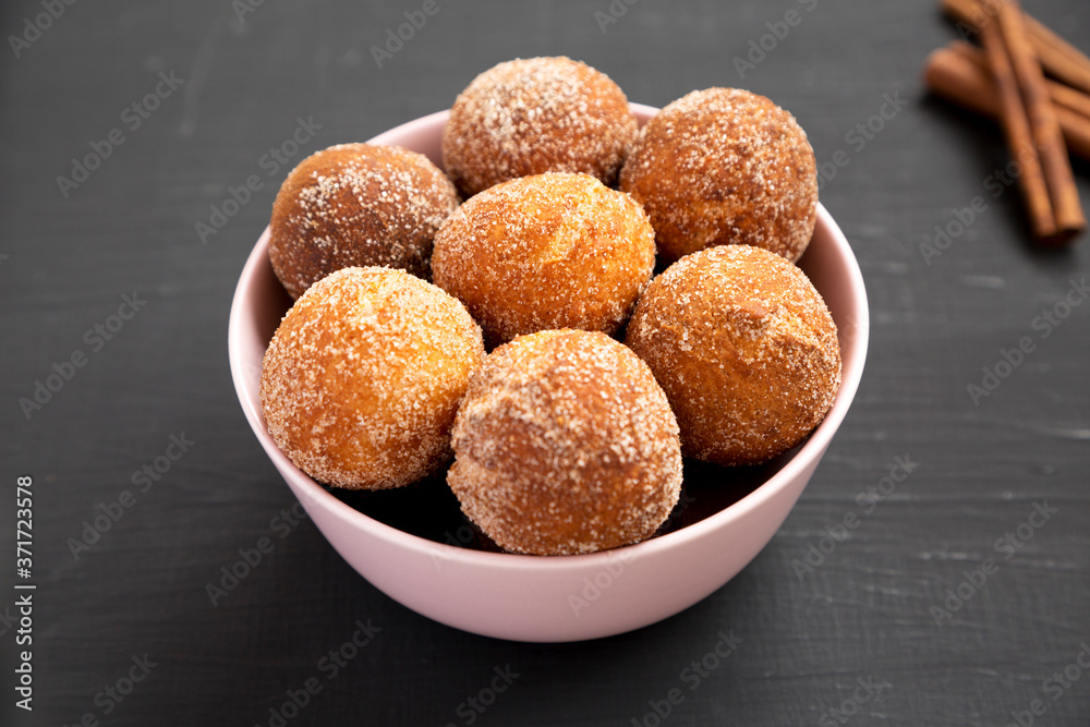Homemade Fried Donut Holes in a pink bowl on a black surface, side view. Homemade Fried Donut Holes in a pink bowl on a black surface, side view.