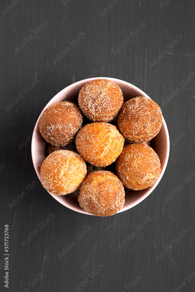 Homemade Fried Donut Holes in a pink bowl on a black background, top view. Flat lay, overhead, from above.