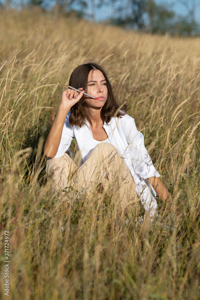 Young European student woman with a book in a field in autumn or summer Young European student woman with a book in a field in autumn or summer