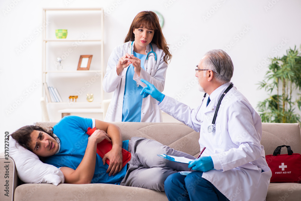 Two doctors visiting sick young man at home Two doctors visiting sick young man at home