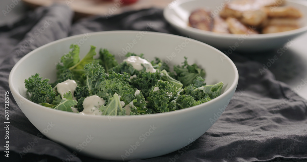 pour caesar dressing on kale leaves in white bowl pour caesar dressing on kale leaves in white bowl