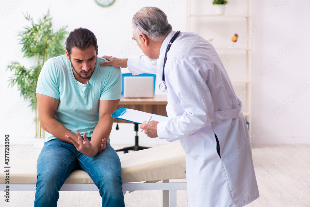 Obraz premium Injured young man visiting old doctor