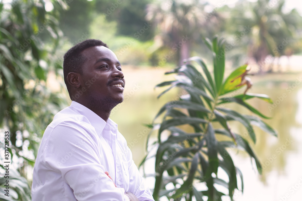African business man in white shirt looking and thinking in green nature African business man in white shirt looking and thinking in green nature