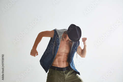 Close up young guy dancer in hat dancing hip-hop in studio isolated on white background. Break dance lessons