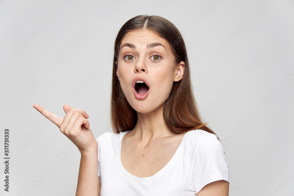 Girl with an open mouth shows a finger to the side on an isolated background Copy Space Girl with an open mouth shows a finger to the side on an isolated background Copy Space