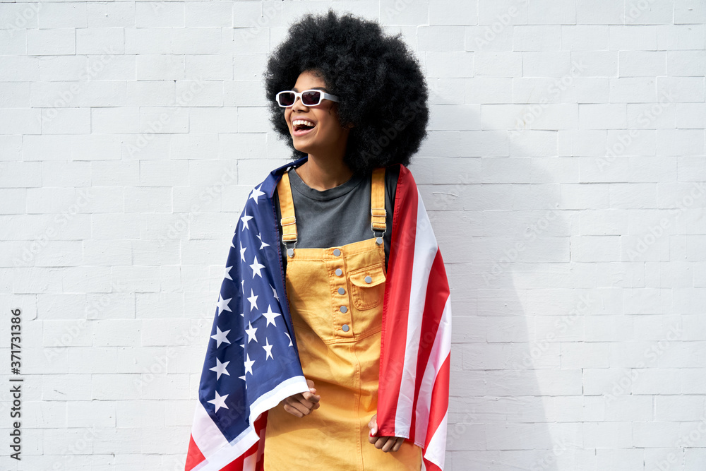 Happy young African American woman wrapped in USA flag laughing ...