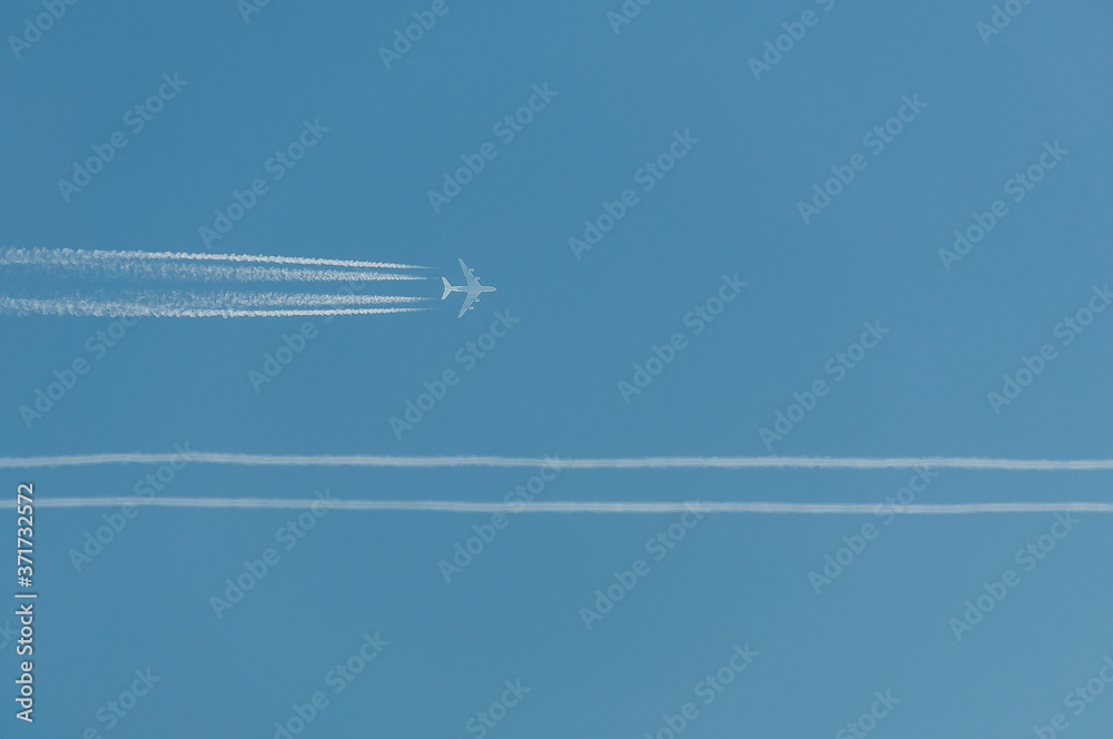 Błękitne niebo z samolotem pasażerskim i smugą kondensacyjną - obrazy, fototapety, plakaty 