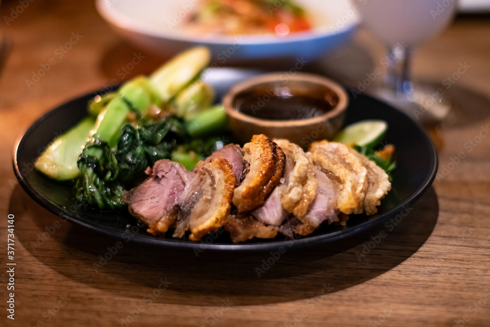 Freshly cooked dinner platter with nice decoration of crisp meat and green vegetables in a restaurant in Bali Freshly cooked dinner platter with nice decoration of crisp meat and green vegetables in a restaurant in Bali