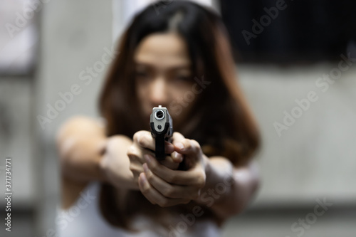 Woman aiming a gun at abandoned house background