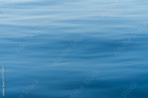 Blur water surface as background. Calm water surface. Blue sea as texture.