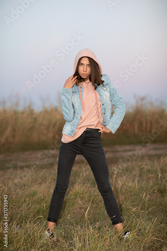 Young European woman or student is posing  in the evening in a field