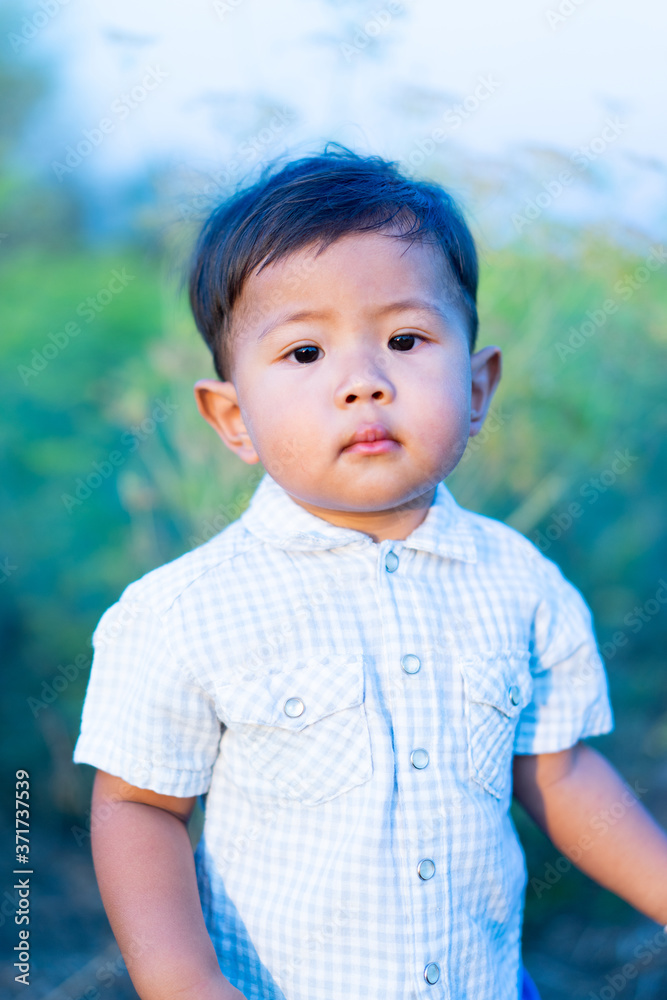 Asian little boy is looking at the camera in the grass field. Asian little boy is looking at the camera in the grass field.