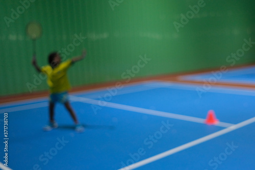 Blur background with little girl training class badminton at  gym.