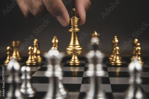Close up hand choose gold chess to challenge with silve chess team on chess board Concept of business strategic plan and professional teamwork and management.