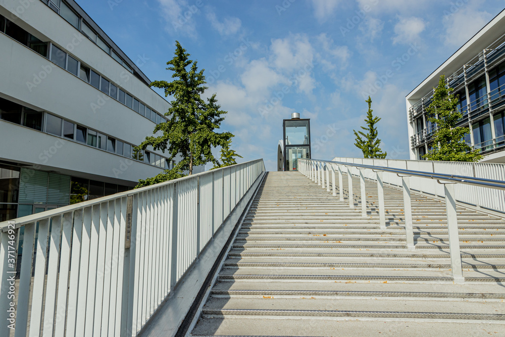 Fototapeta premium Low perspective of the stairs of the High Bridge (Hoge Brug) with its elevator. Bicycle or pedestrian bridge over Maas (Meuse) in Maastricht, sunny day in South Limburg, Netherlands